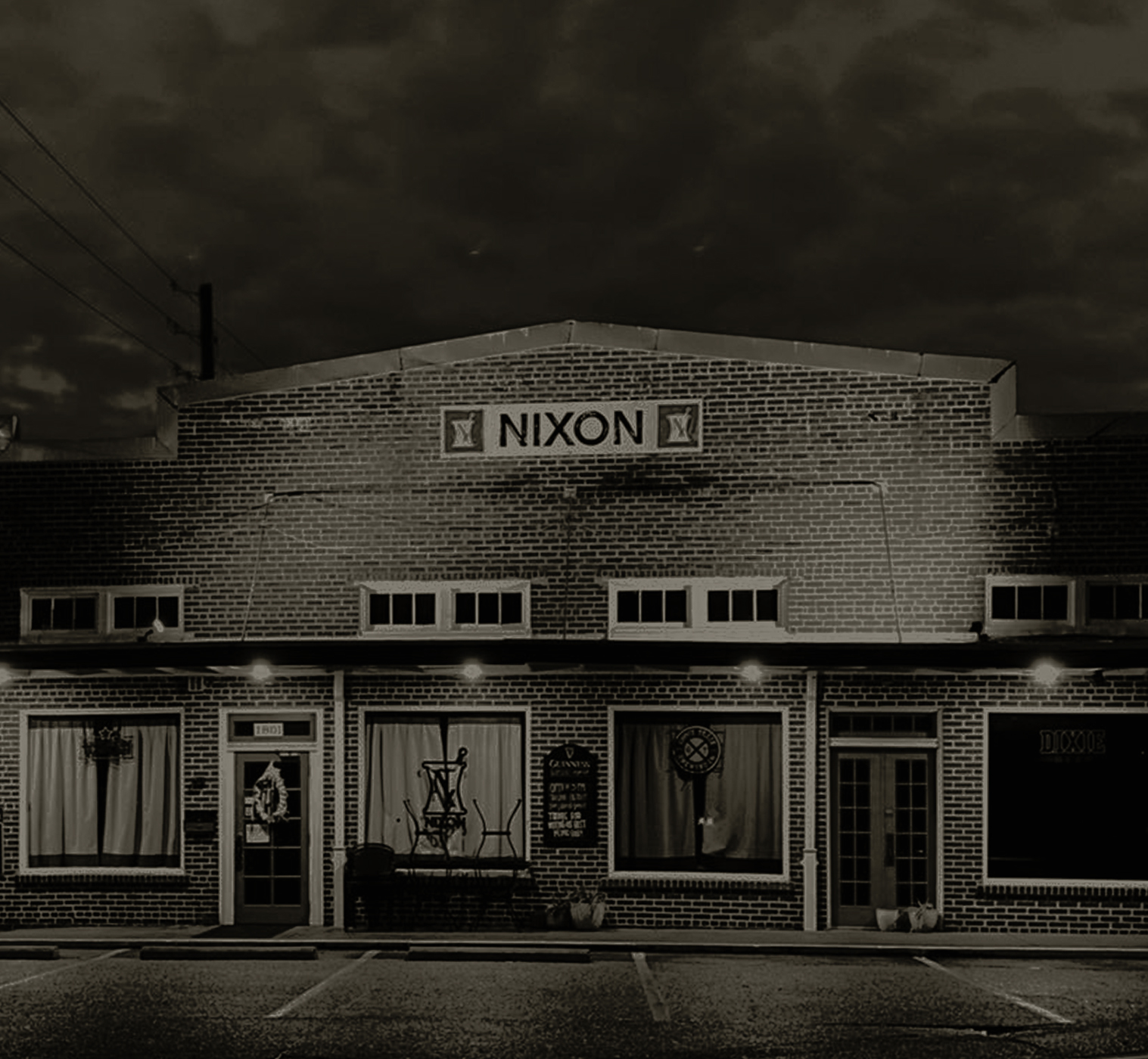 Dramatic black and white exterior of the Nixon's Midtown brick building with a moody overcast sky